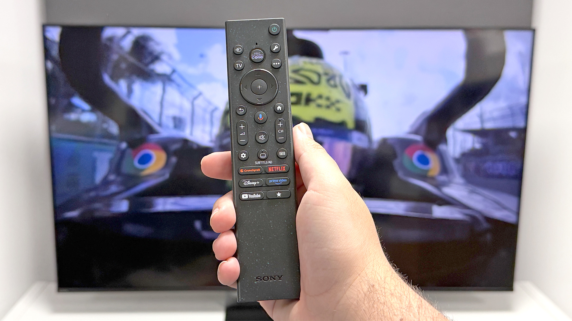 Sony Bravia 7 II RGB Mini LED TV with remote control held. in hand in front of screen