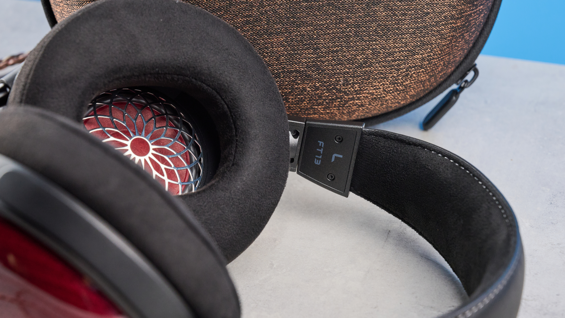 the fiio ft13 wired headphones with wood cups and copper cable photographed against a blue background