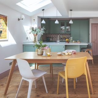 A dining room connected to the kitchen with an extendable dining table and mismatched dining chairs