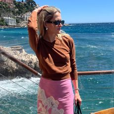 Eliza Huber in Nice, France wearing a Zara brown V-neck sweater with a pink printed Zara skirt.