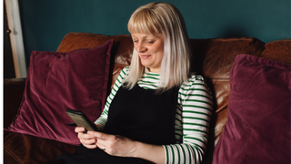 Woman on phone at home, sitting on sofa and smiling