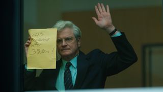 Jim Swire (Colin Firth) holds up a note reading "103 exploded after 38 mins!" as seen in Peacock and Sky's "Lockerbie: A Search for Truth"