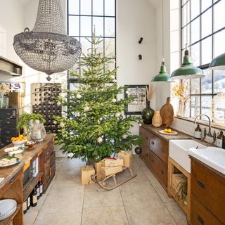 large kitchen with double height windows an large Christmas tree and traditional sledge with reclaimed kitchen units