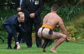Britain's Prince William (L) picks up the dart from a Maori warrior (R) during a Maori welcoming ceremony at Government House in Wellington on April 7, 2014. Britain's Prince William, his wif