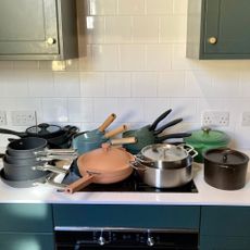 Multiple pots and pans on the kitchen counter top stacked over the stove