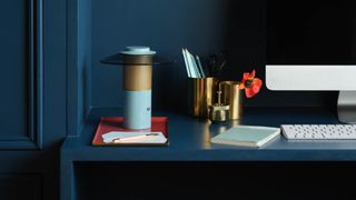 a wireless table lamp on a blue desk