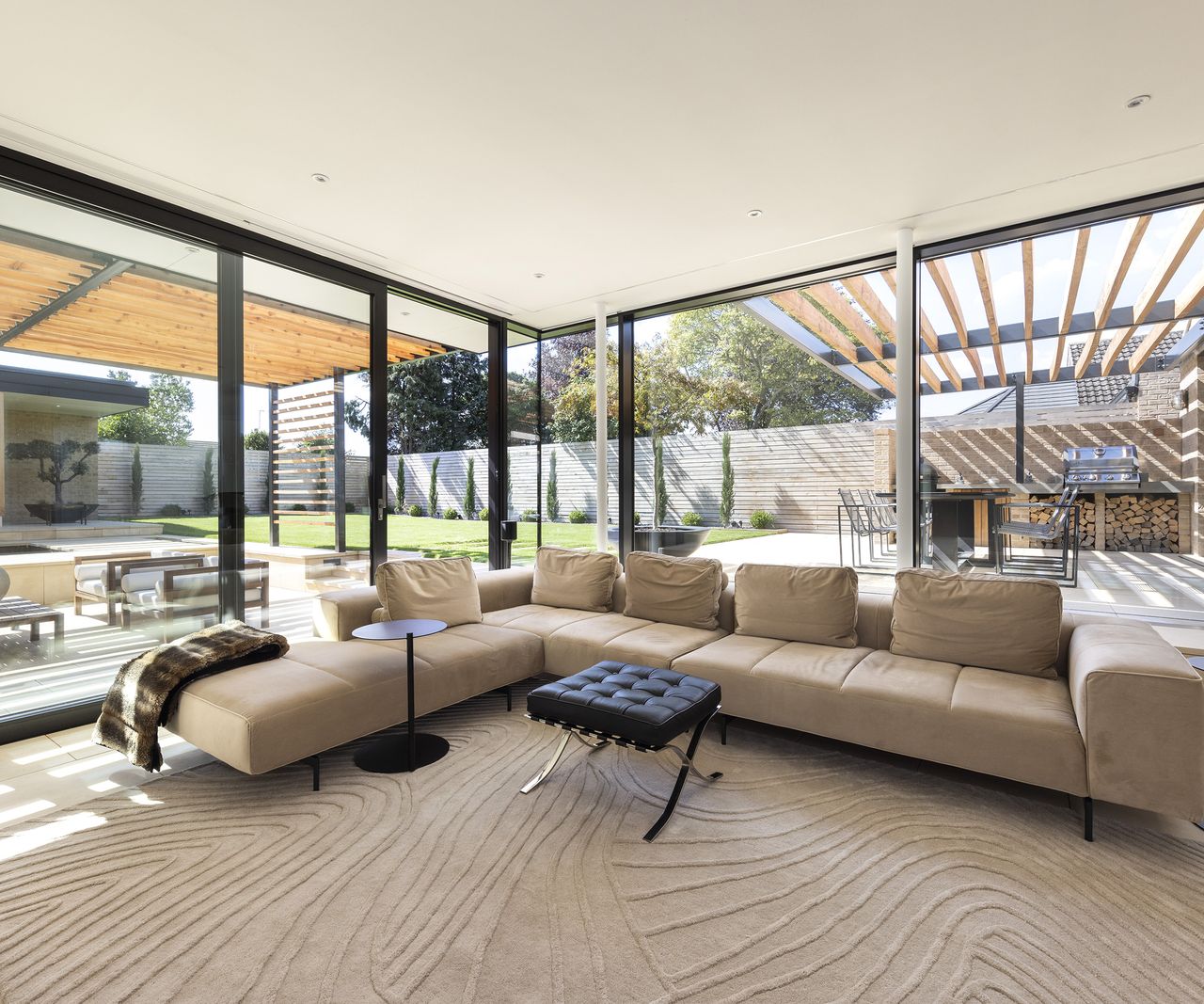 large beige corner sofa in lounge with floor to ceiling glass windows and sliding doors