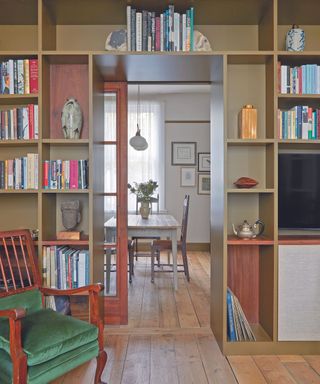 Wall of shelving used as divider between a living room and a dining room