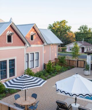 Exterior of pink house over pool with blue striped umbrellas