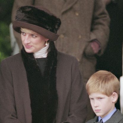 Princess Diana wearing a brown coat with fur trim and matching hat standing next to Prince Harry outside of church