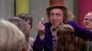 Willy Wonka holds up some gum in front of a group of kids