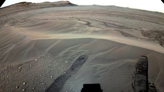 sandy hills on mars with tracks from a rover visible in the front