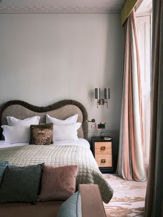 Neutral bedroom with wavy headboard trimmed with brown fringing