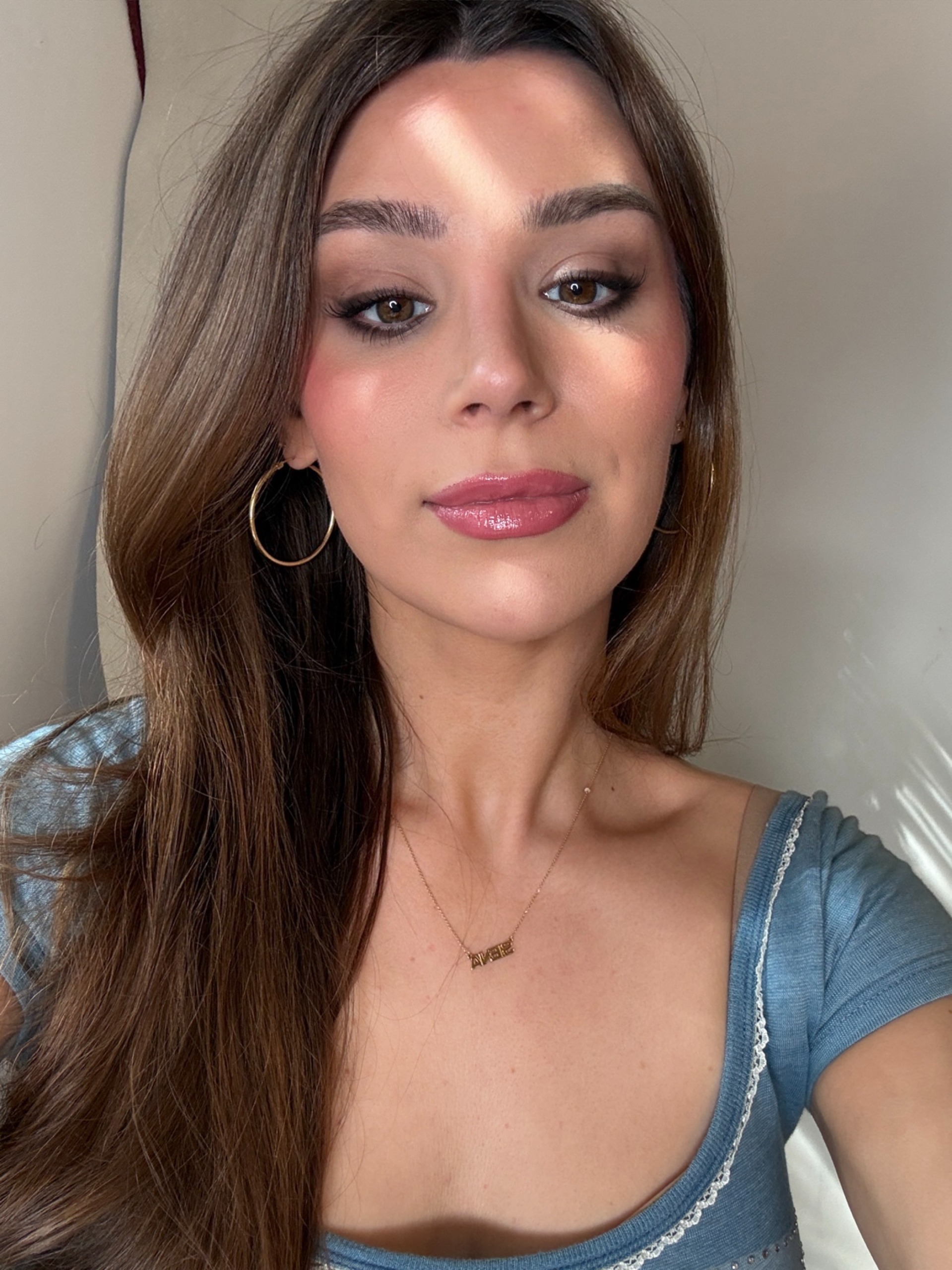 a girl with a blue shirt on, gold hoops, and soft style nanobrows
