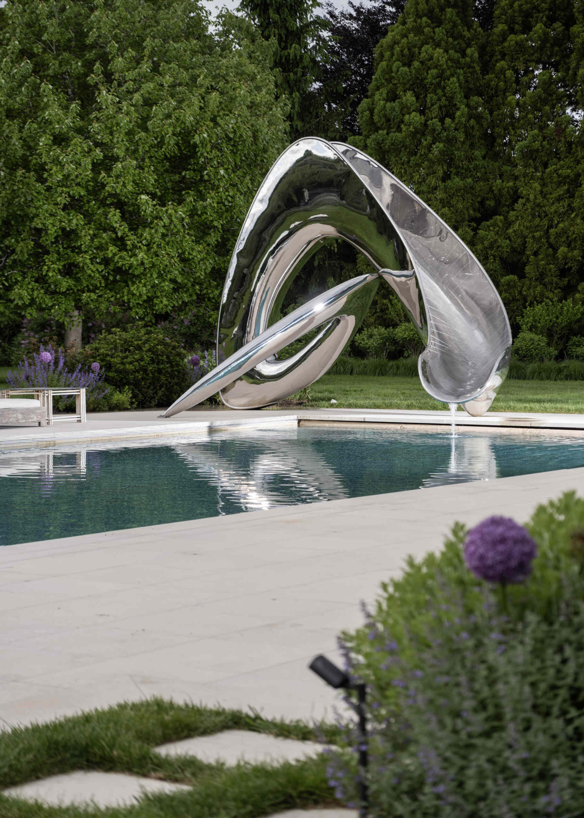 spinterworks chrome stainless steel sculptural slide in an outside pool