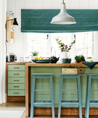 Green painted kitchen island with green painted stools in white kitchen 