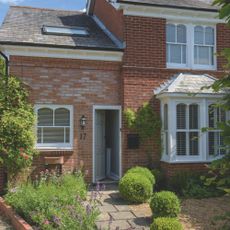 Front of a brick house with plants and gravel front garden