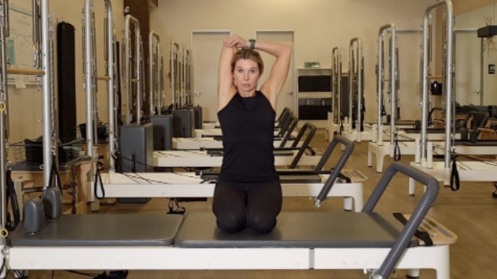 Woman on a Reformer Pilates machine demonstrating an exercise