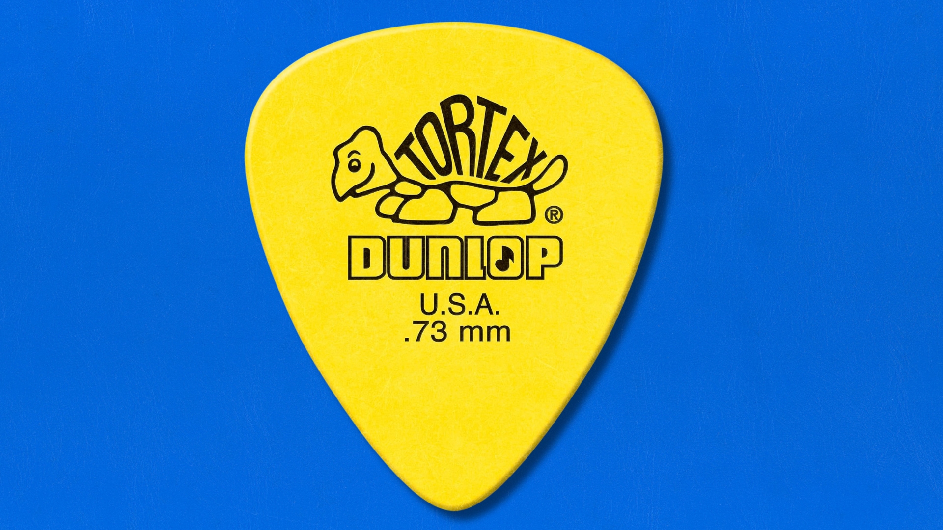 A Jim Dunlop Tortex guitar pick on a blue background