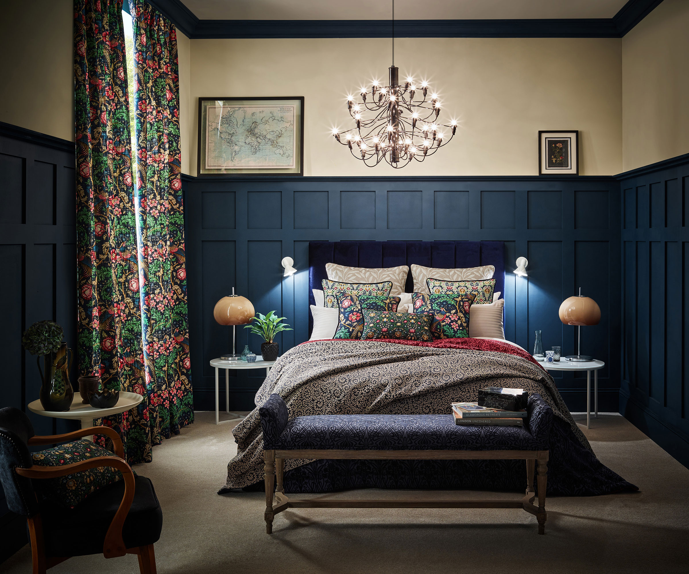double bedroom with blue velvet bed and blue wall panelling with green patterned curtains