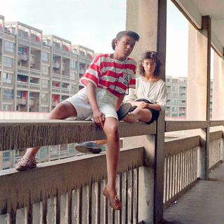Donna Hargreaves and Carmen Bello sit on an unguarded fourth storey concrete parapet. Hyde Park Flats, Sheffield, 1988, by Bill Stephenson