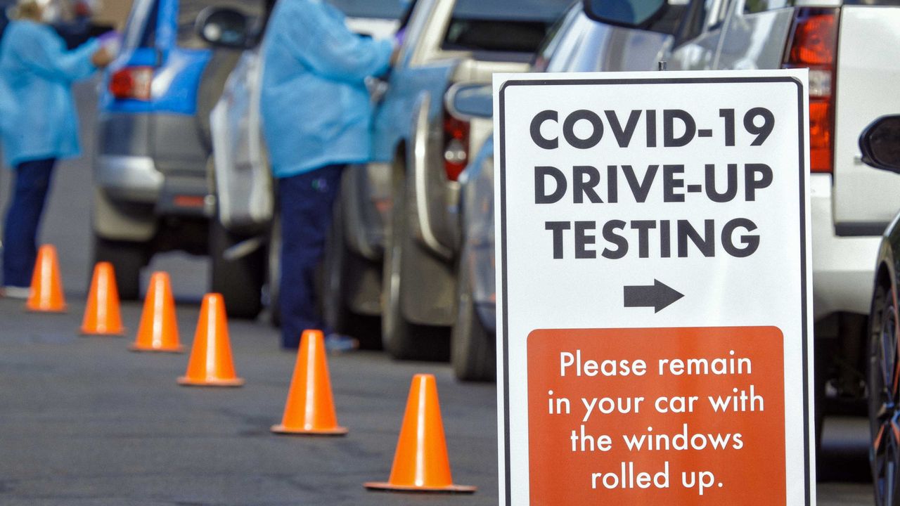 Cars wait in line at a COVID-19 drive-up testing station