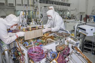 Technicians at NASA's Jet Propulsion Laboratory in Pasadena, California, integrate the rover motor controller assembly (RMCA) into the Mars 2020 rover's body in April 2019. The RMCA commands and regulates the movement of the motors in the rover's wheels, robotic arms, mast, drill and sample-handling functions. 
