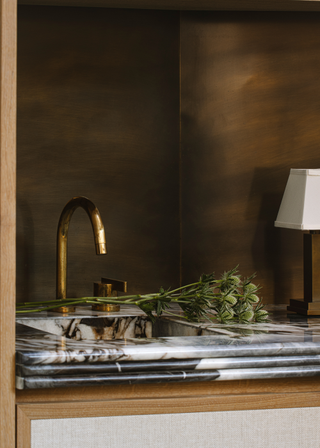 Bronze recessed sink area with a copper tap and marble surface with a triple layered edge design