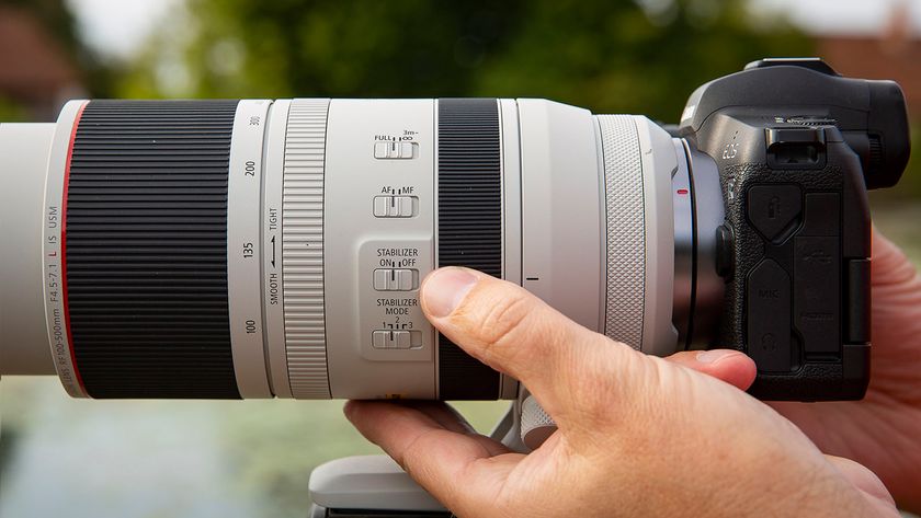 Close-up of a person adjusting settings on a professional camera lens, highlighting focus and stabilization controls