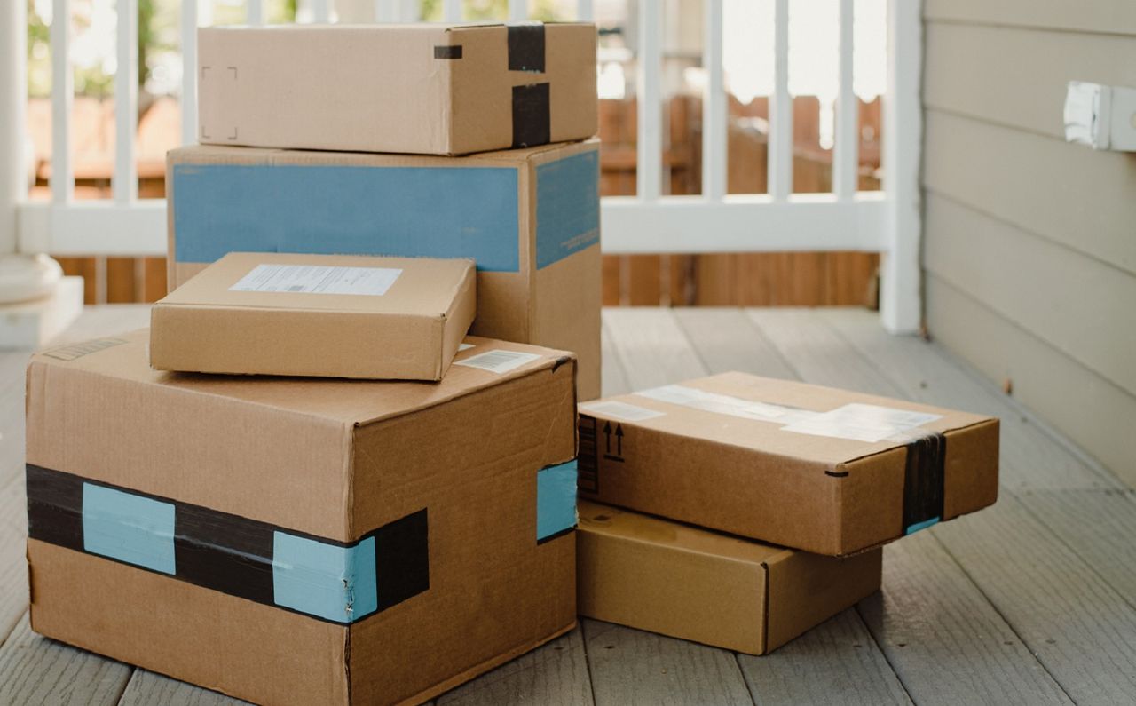 Stack of unopened box packages on porch of home.