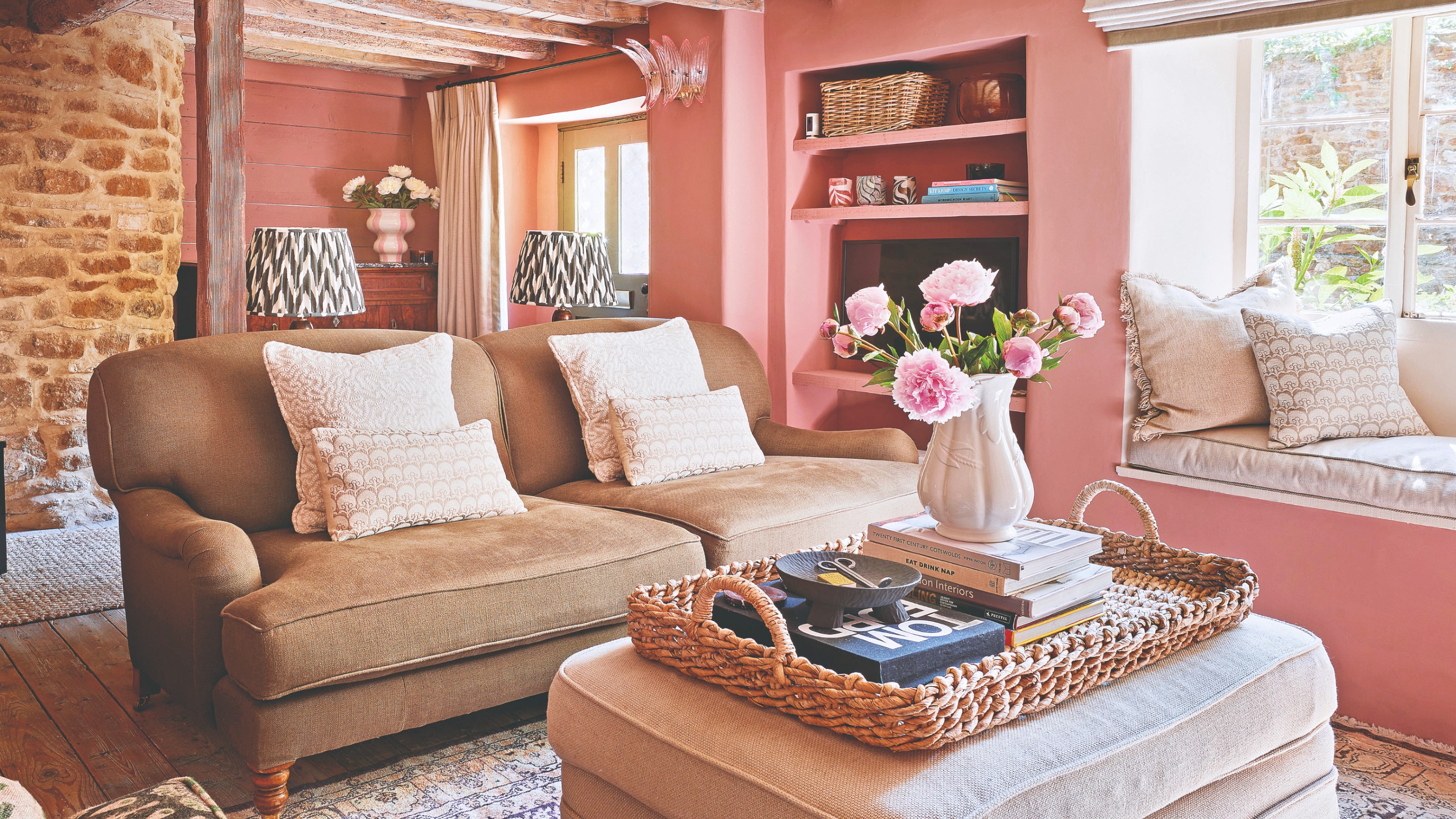 A pink-painted cottage-style rustic living room with a window seat and a traditional-style beige sofa 