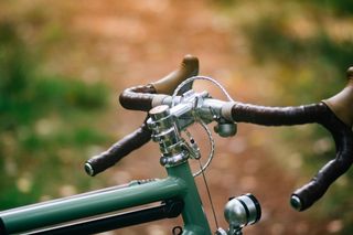 The front of a bike with silver bars and stem, brown tape, and no computer