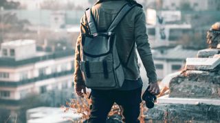 man wearing a camera backpack stood at a viewpoint
