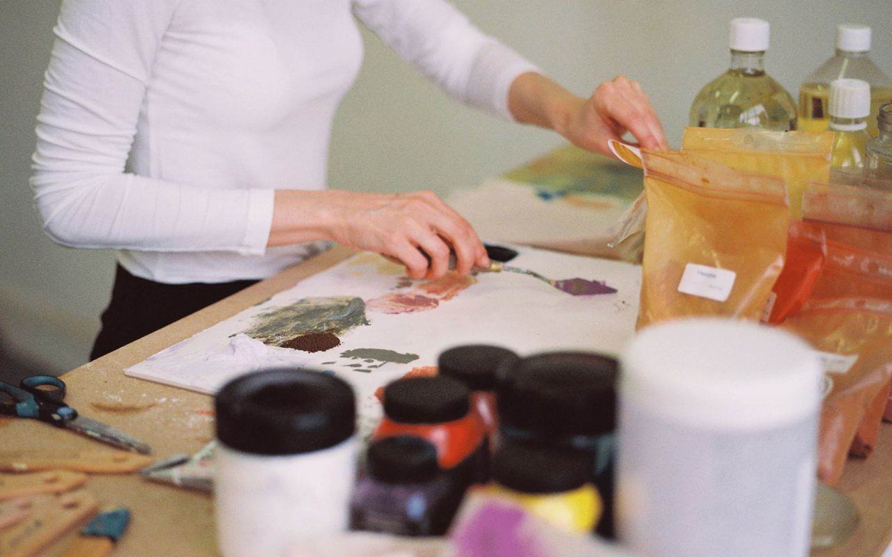 A painter at work in her studio places patches of pigment onto the canvas.