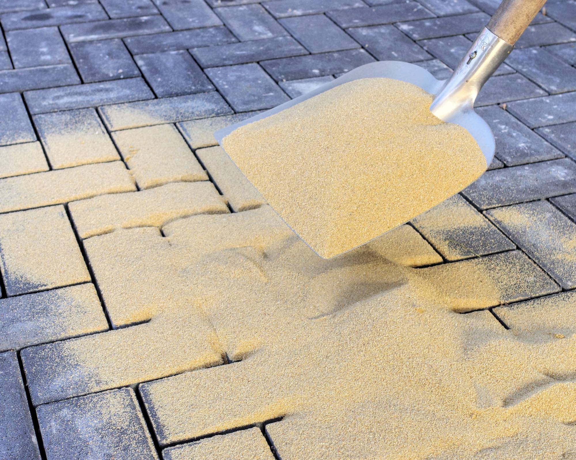 Polymeric sand being applied to pavers