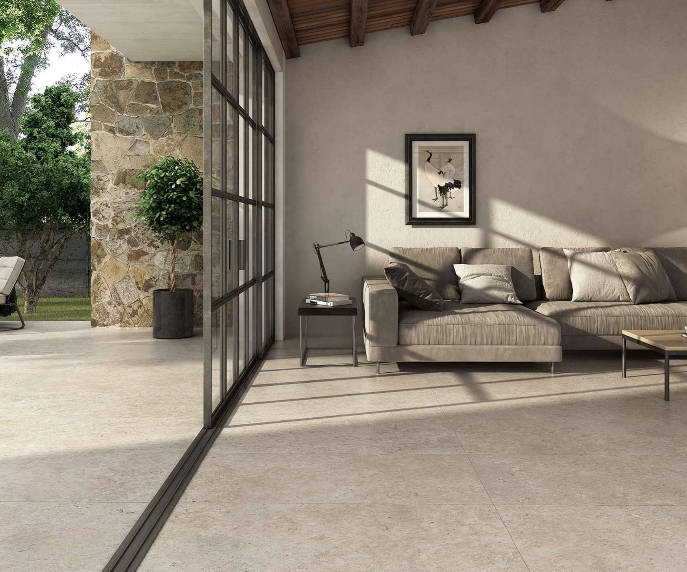 A seamless indoor&amp;ndash;outdoor living space with large-format stone-look tiles running from the sitting room to the patio. Neutral tones, natural light and a modern sectional sofa create a calm, contemporary feel perfect for open-plan homes.