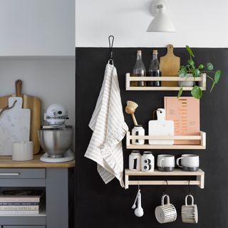 Ikea spice racks used as wall shelves on a black wall in a kitchen