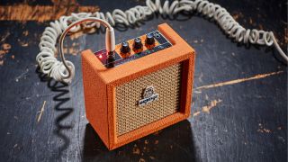 An Orange Crush Mini desktop guitar amp on a wooden floor