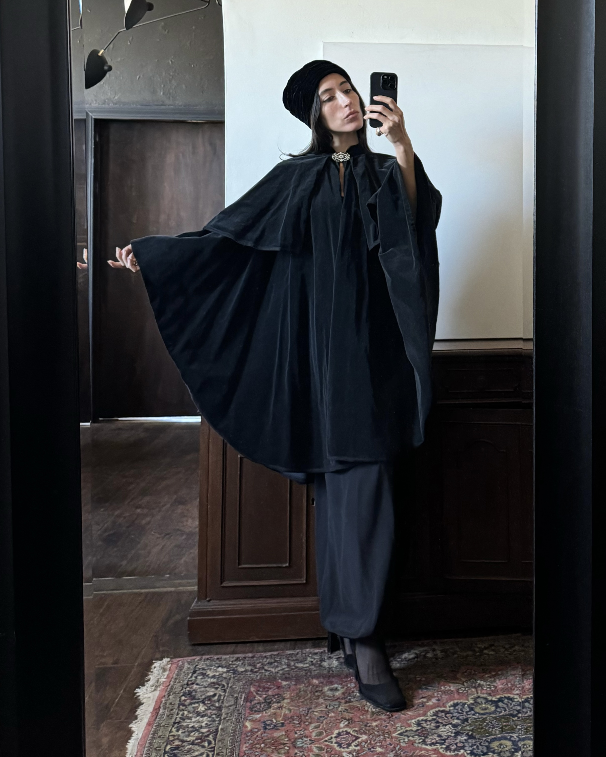 Alexis Badiyi wearing a black cape and black pants,