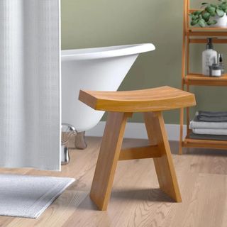 A wooden shower stool in a green bathroom