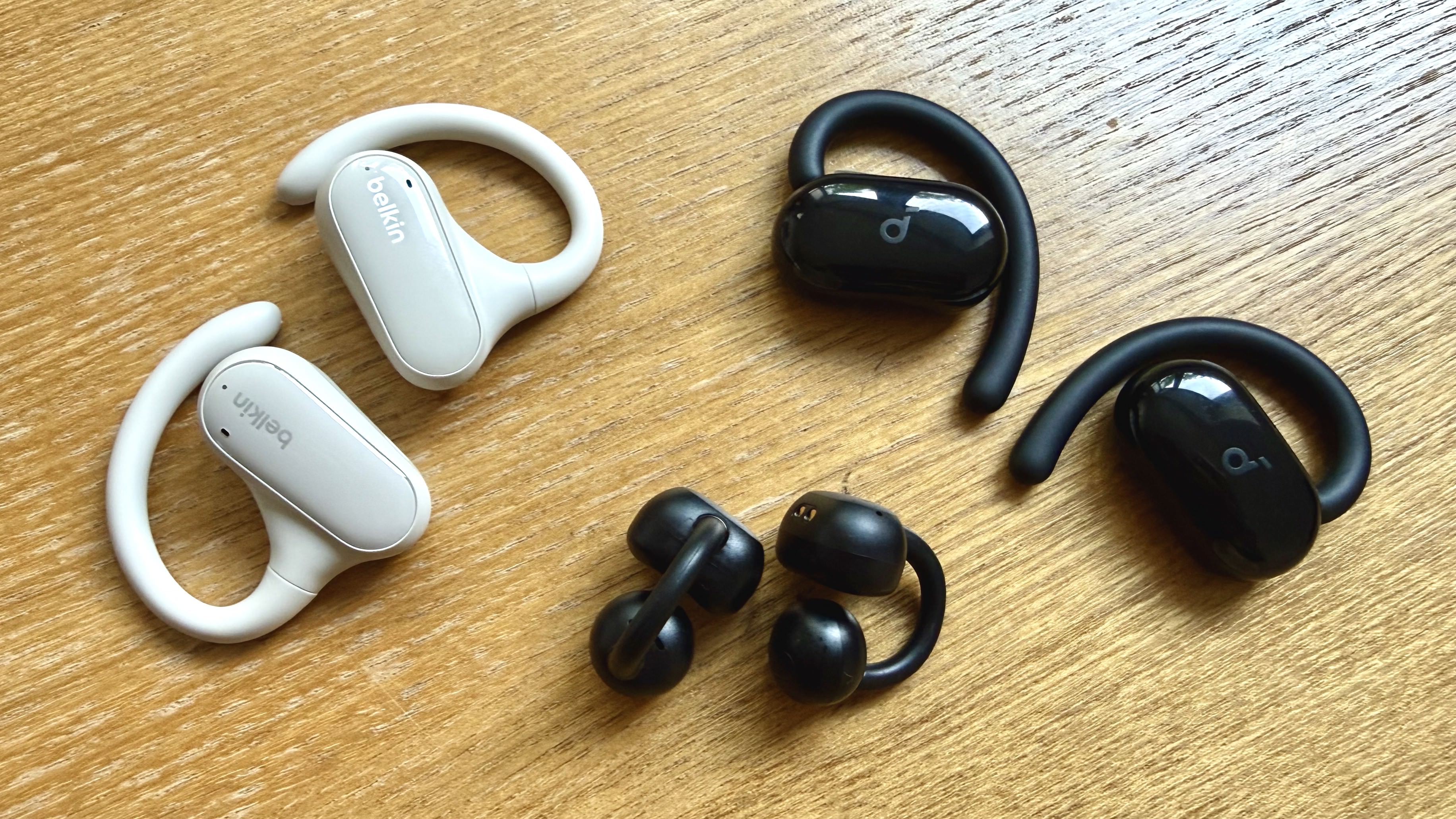 Three pairs of cheap open earbuds pictured on a wooden surface
