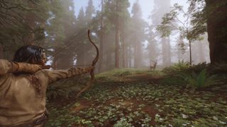 Long-haired man aims drawn bow toward deer standing at a distance in a foggy forest