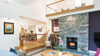 split level living room with exposed stone wall and mezzanine level