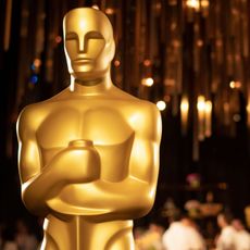Closeup of an Oscar award with the ceremony in the background.