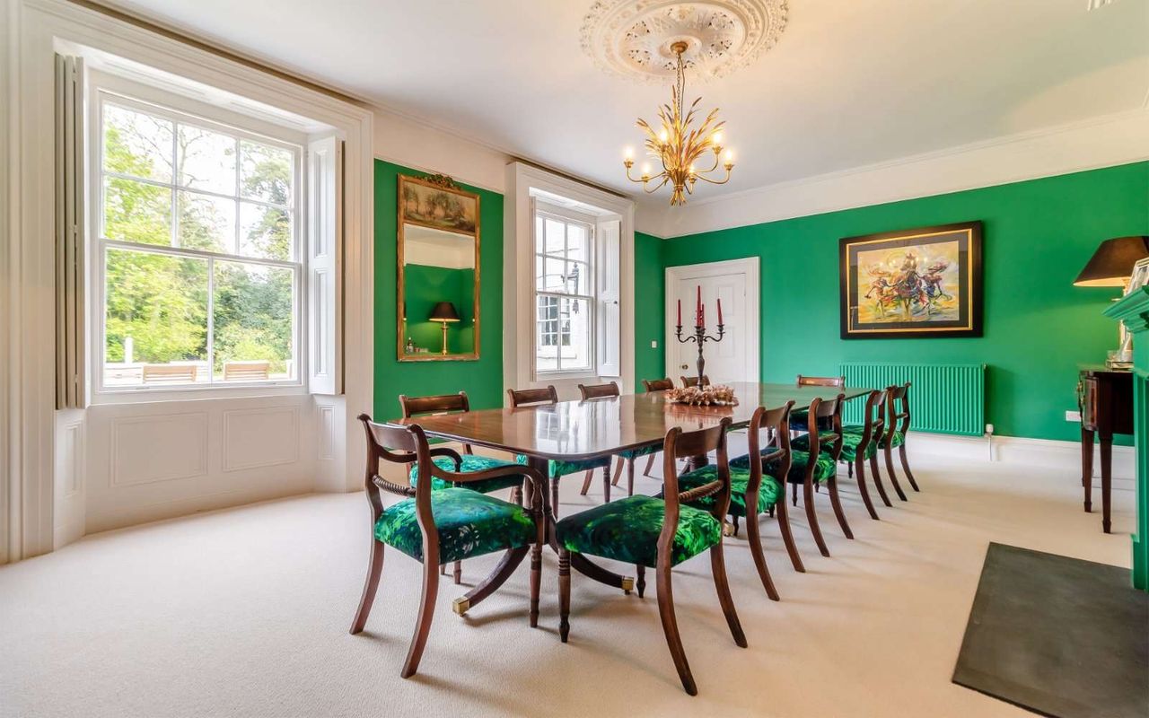 A dining room in Saham Lodge. IT has green walls, white ceiling, and is quite traditional in style