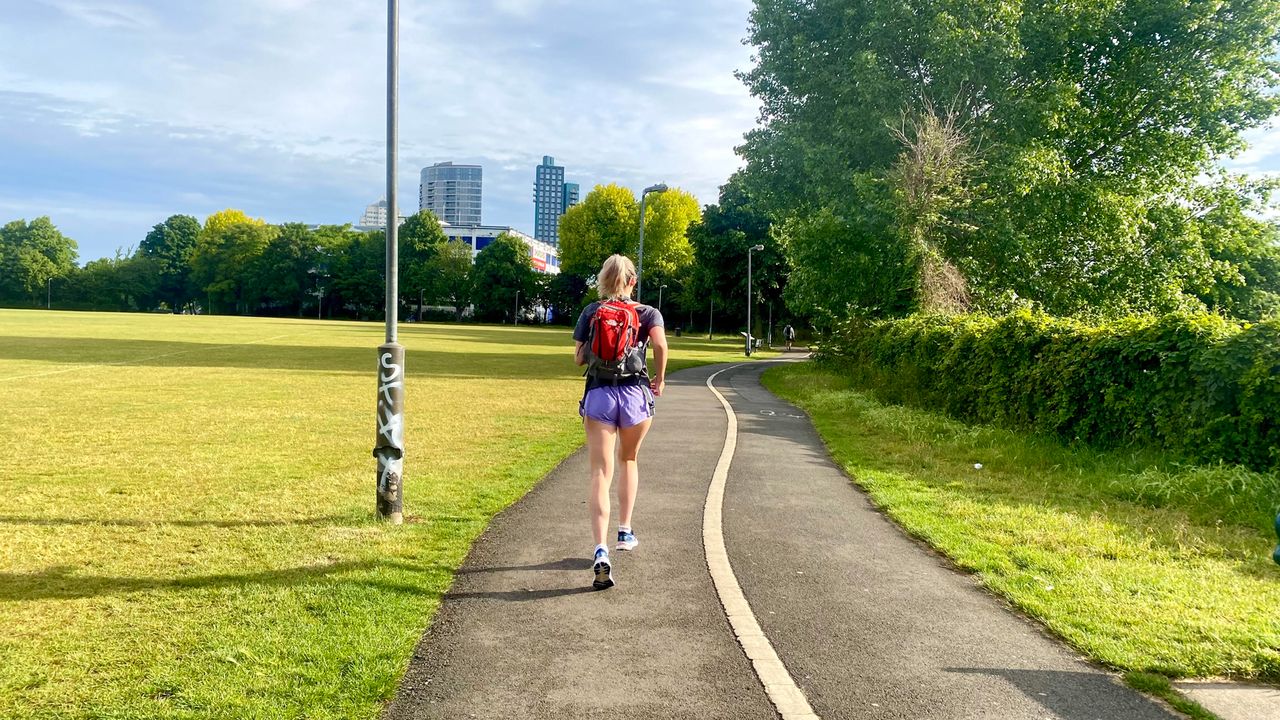 Fit&amp;Well writer Jessica Downey runs through a park wearing a backpack