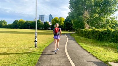 Fit&Well writer Jessica Downey runs through a park wearing a backpack
