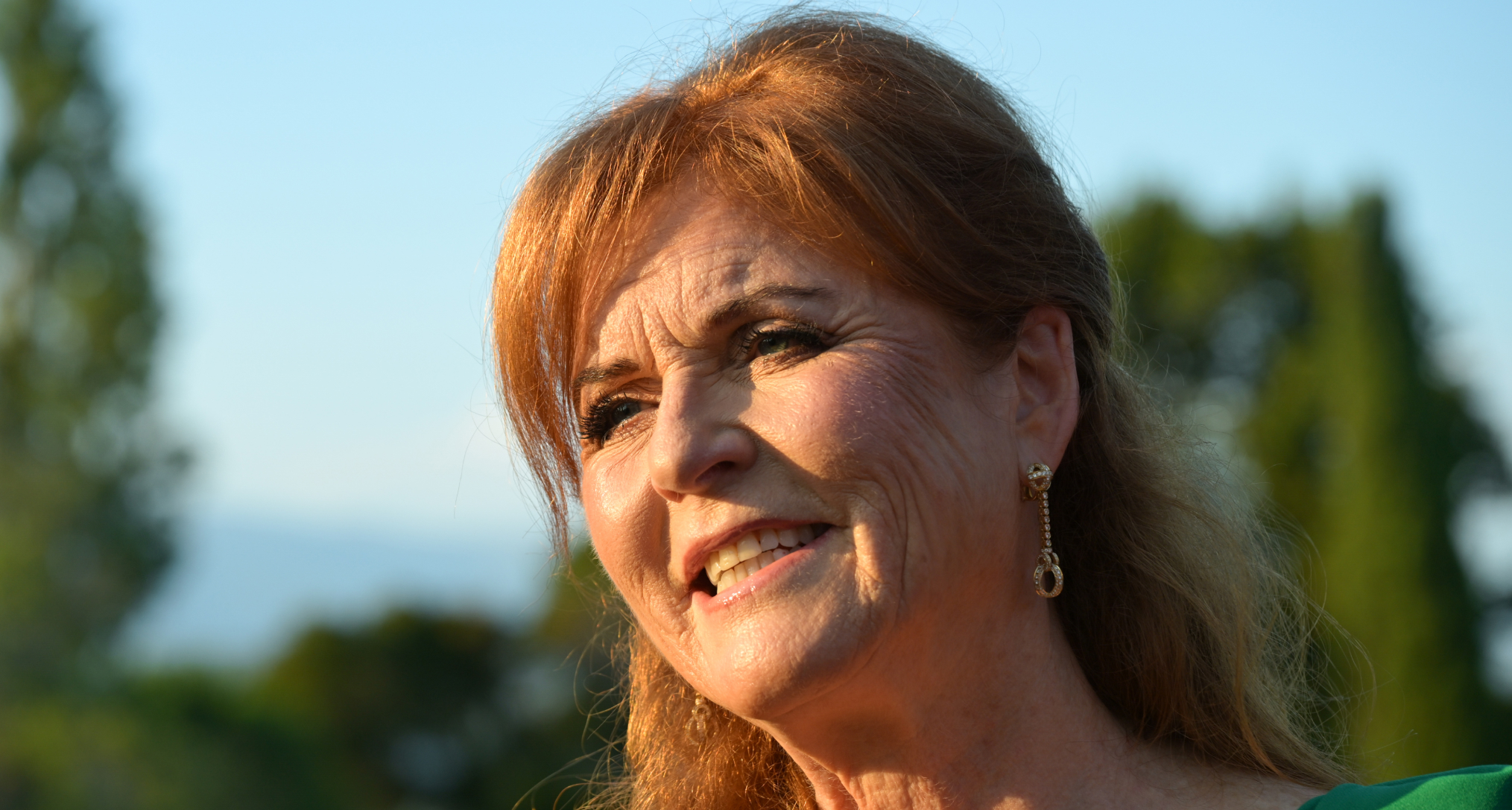 A headshot of Sarah Ferguson smiling in front of some trees