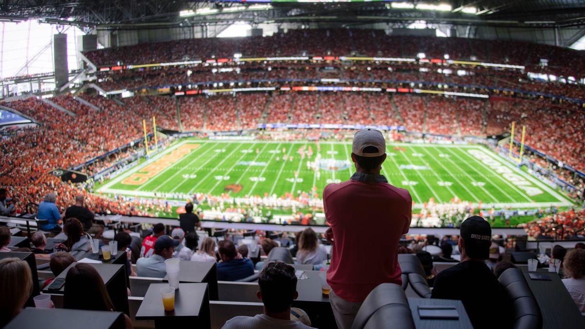 A fan stands watching college football on an 87-foot LED screen.