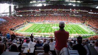 A fan stands watching college football on an 87-foot LED screen.